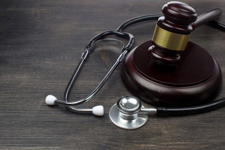 A gavel and a stethoscope placed on a brown table