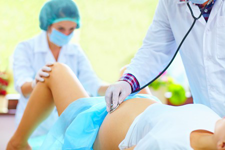 A woman undergoing childbirth under the care of a doctor and a nurse